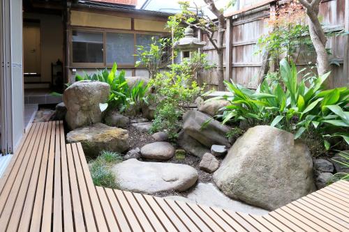 einen Garten mit Felsen und Pflanzen vor einem Gebäude in der Unterkunft Nara Guesthouse Kamunabi in Nara