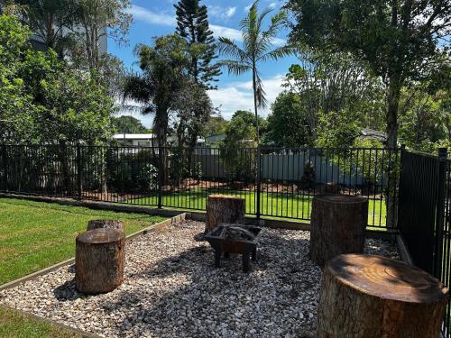 a park with a bench and three tree stumps at Little Ray on Sunshine. Hamptons style beachhouse in Woorim
