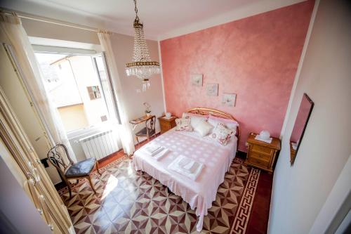 - une chambre avec un lit aux murs roses et un lustre dans l'établissement Profumo di casa, à La Spezia