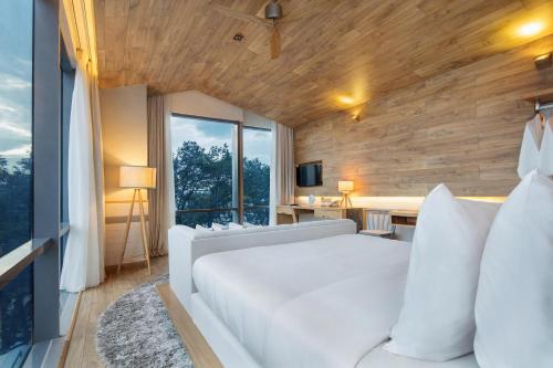 a bedroom with a white bed and a large window at Fusion Suites Saigon in Ho Chi Minh City
