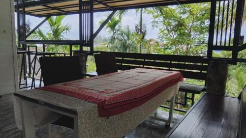 a table and chairs on a porch with a view of the forest at Chalisa Bukit House Lanta in Ko Lanta