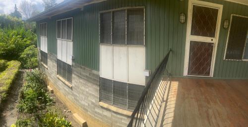 a green house with a porch and a door at GOROKA Home Stay in Goroka