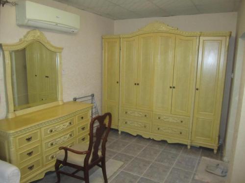 - une chambre avec une commode, un miroir et une chaise dans l'établissement العين الهيلي مصباح ب1, à Al-Aïn