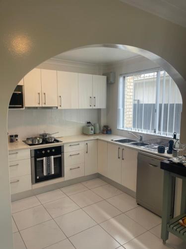 a kitchen with white cabinets and a large window at 2 Bed Ground Flr Gaythorne Courtyard Apt, parking in Brisbane