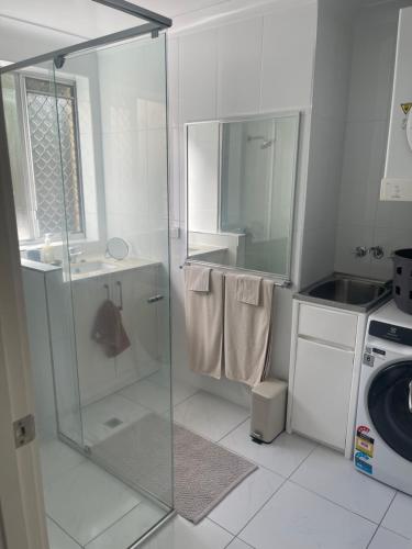 a white bathroom with a shower and a sink at 2 Bed Ground Flr Gaythorne Courtyard Apt, parking in Brisbane