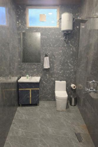 a bathroom with a toilet and a sink and a mirror at Mud Meadows - Peace and Tranquility 3br Farm in Faridabad
