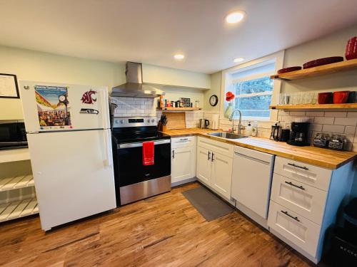a kitchen with white cabinets and a white refrigerator at State Street Cottage, Suite 1 in Pullman
