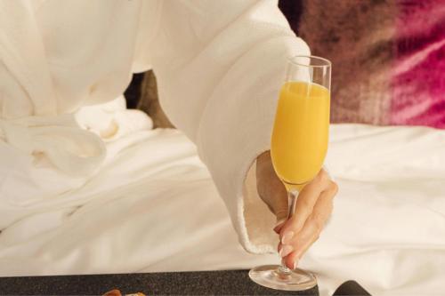 een persoon houdt een glas sinaasappelsap vast bij THE MIDLAND HOTEL, Chicago, a Tribute Portfolio Hotel in Chicago