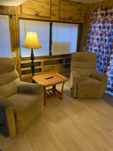 a living room with two chairs and a table and a lamp at Park Model Furnished #5 in Tucson