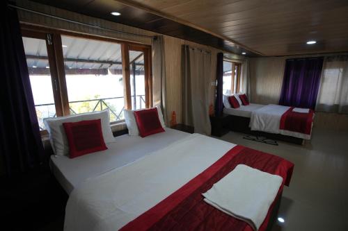 ein Schlafzimmer mit zwei Betten mit roten und weißen Kissen in der Unterkunft Himalaya View Resort in Mukteswar