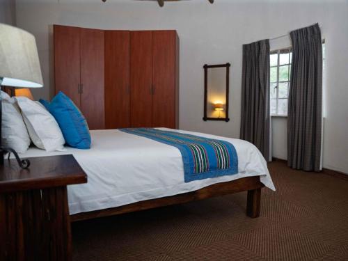 a bedroom with a large white bed with blue pillows at Awelani Eco Tourism Lodge in Masisi