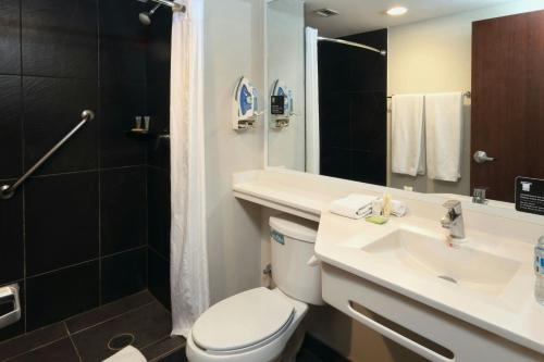 a bathroom with a toilet and a sink and a shower at City Express Plus by Marriott Monterrey Galerías in Monterrey