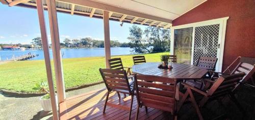 a table and chairs on a porch with a view of the water at Christian's Minde, Jervis Bay in Sussex inlet