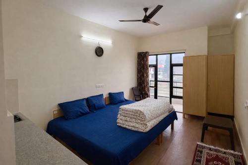 - une chambre avec un lit bleu et un ventilateur de plafond dans l'établissement LVMR MIDTOWN STUDIO APARTMENT Shamshi, à Kulu