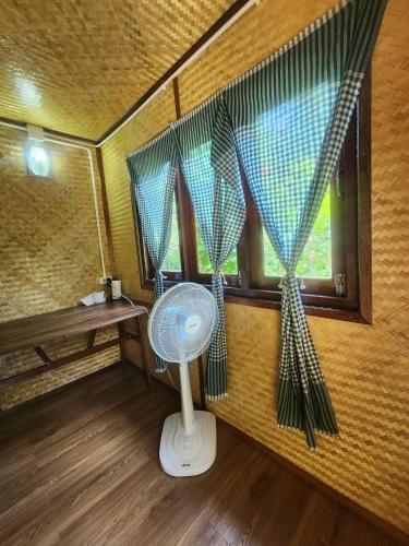 a room with a fan and a window with curtains at Mook Bamboo Bungalows in Ko Mook