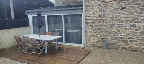 een tafel en stoelen op een houten terras bij Gîte L'hôtellerie in Trévron