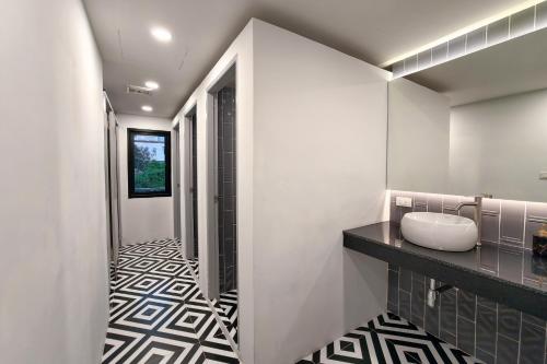 een badkamer met een wastafel en een zwart-witte tegelvloer bij The Rich Cafe & Hostel in Pattaya South
