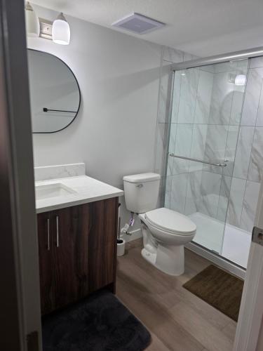a bathroom with a toilet and a sink and a shower at YYC Cozy Suites in Calgary