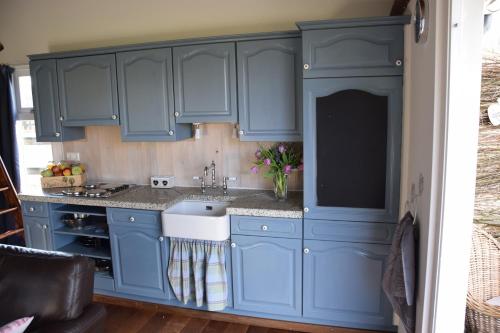 una cocina con armarios azules y fregadero en t Appelstekje, en Appeltern