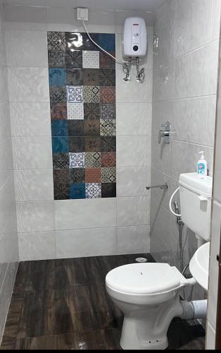 a bathroom with a toilet and a tile wall at Costa Rica in Kumta