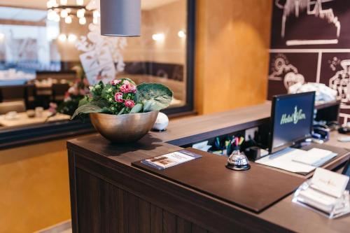 a reception desk with a bowl of flowers on a counter at Hotel Sion in Cologne
