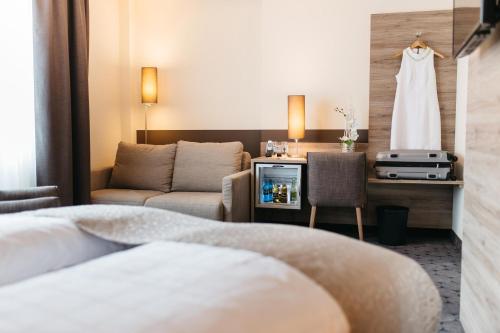 a hotel room with a couch and a dress hanging on a wall at Hotel Sion in Cologne