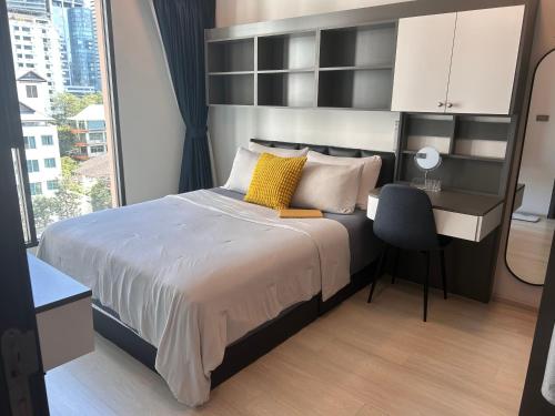 ein Schlafzimmer mit Bett, Schreibtisch und Fenster in der Unterkunft Sukhumwit Soi 10 at VENiO in Klong Toi