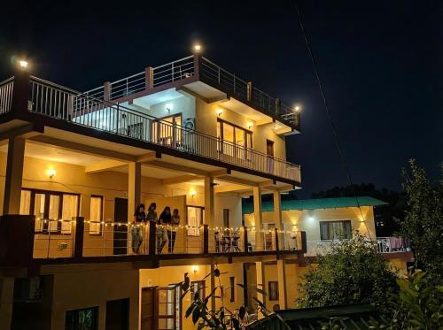 ein Gebäude mit Menschen, die nachts auf einem Balkon stehen in der Unterkunft Rooptara Valley Luxury Cottage Majkhali Himalaya in Rānīkhet
