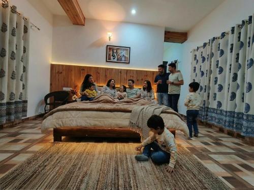 eine Gruppe von Personen in einem Schlafzimmer mit einem Bett in der Unterkunft Rooptara Valley Luxury Cottage Majkhali Himalaya in Rānīkhet