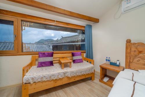 a bedroom with a bed and a window with purple pillows at Travel & Rest Inn in Lijiang