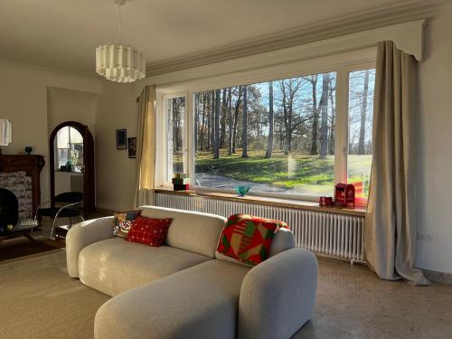 a living room with a couch and a large window at Aux étangs fleuris in Rochefort