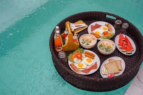un vassoio di cibo per la colazione su un tavolo accanto a una piscina di Kaija Resort a Ko Larn
