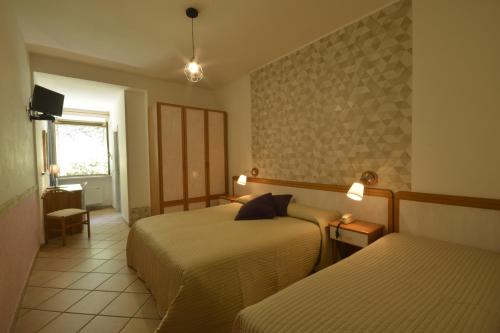 a hotel room with two beds and a desk at Hotel Pineta Ristorante country house in Fabriano in Campodonico