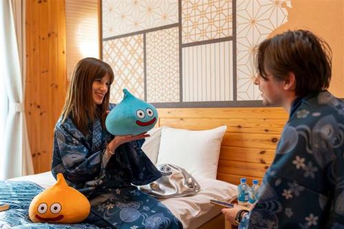 a woman sitting on a bed holding a fish toy at GRAND CHARIOT Hokutoshichisei 135° in Awaji