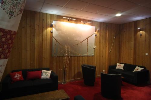 a room with two couches and a large clock on the wall at Hôtel L'Escale Blanche in Les Orres