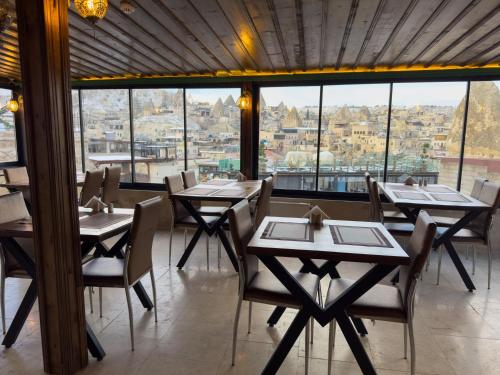 a restaurant with tables and chairs and a large window at Alaca Cave Cappadocia in Goreme