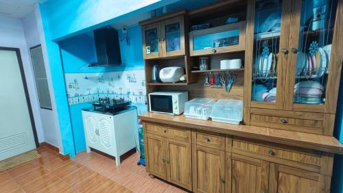 una cucina con armadi in legno e parete blu di บ้านปรินรดา poolvilla สัตหีบ a Sattahip