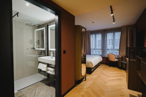 a hotel room with a bathroom with a bed and a sink at Hota Hotel Porrentruy in Porrentruy