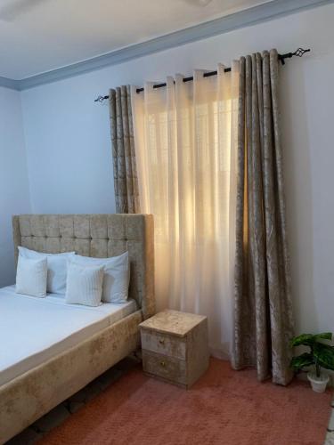 ein Schlafzimmer mit einem Bett und einem Fenster mit Vorhängen in der Unterkunft Casa Bellah Sunrise in Watamu