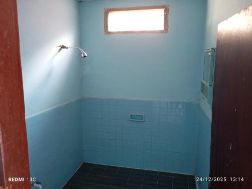 a bathroom with a blue wall and a window at Alexander Homestay in Tuktuk Siadong
