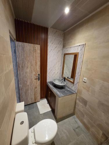 a bathroom with a toilet and a sink at Tebanyoman Guesthouse in Dalung