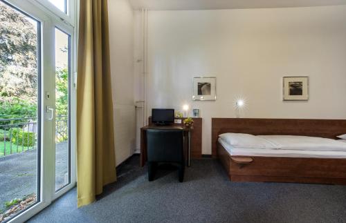 a bedroom with a bed and a desk and a window at CJD Bonn Castell in Bonn