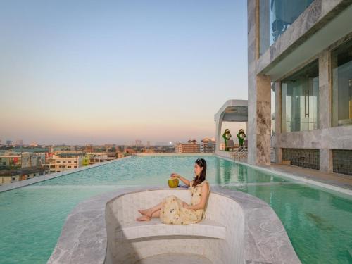 une femme assise au bord d'une piscine dans l'établissement 酒店MARQUIS HOTEl, à Ban Bang Toei (1)