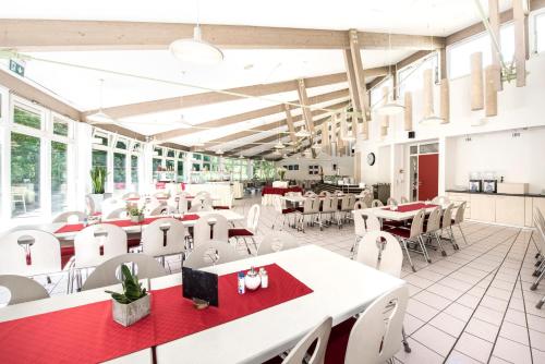 un restaurante con mesas blancas y sillas blancas en CJD Bonn Castell, en Bonn