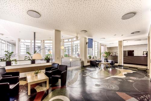 a lobby with black chairs and tables and windows at CJD Bonn Castell in Bonn
