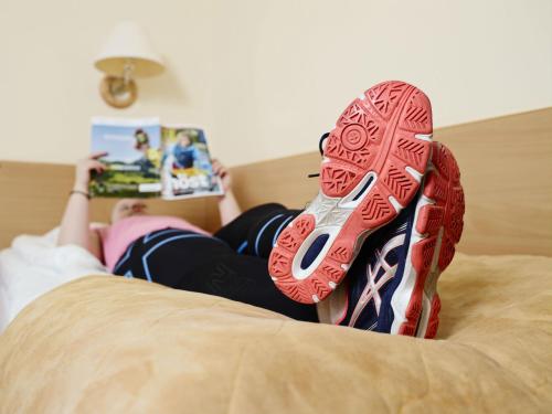 a woman laying on a bed with red shoes on her feet at Hotell Sport & Rest in Bergsviken