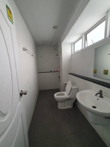 a white bathroom with a toilet and a sink at Royal Himalayan Hostel in Ban Phraek Sa