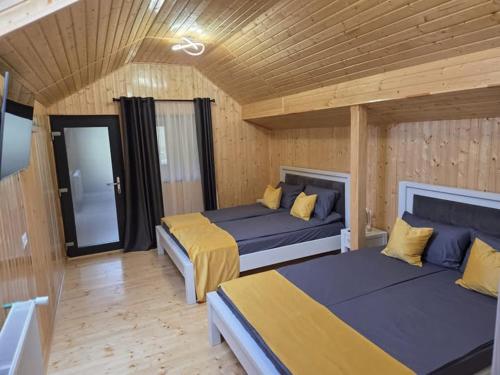 2 Betten in einem Zimmer mit Holzwänden und Holzböden in der Unterkunft Pensiunea Dariana in Bucium-Sat
