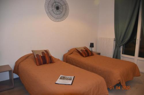 2 bedden met oranje lakens in een kamer bij Villa Lumières in Goult