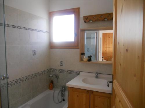 La salle de bains est pourvue d'un lavabo, d'un miroir et d'une baignoire. dans l'établissement les gentianes, à La Salle Les Alpes